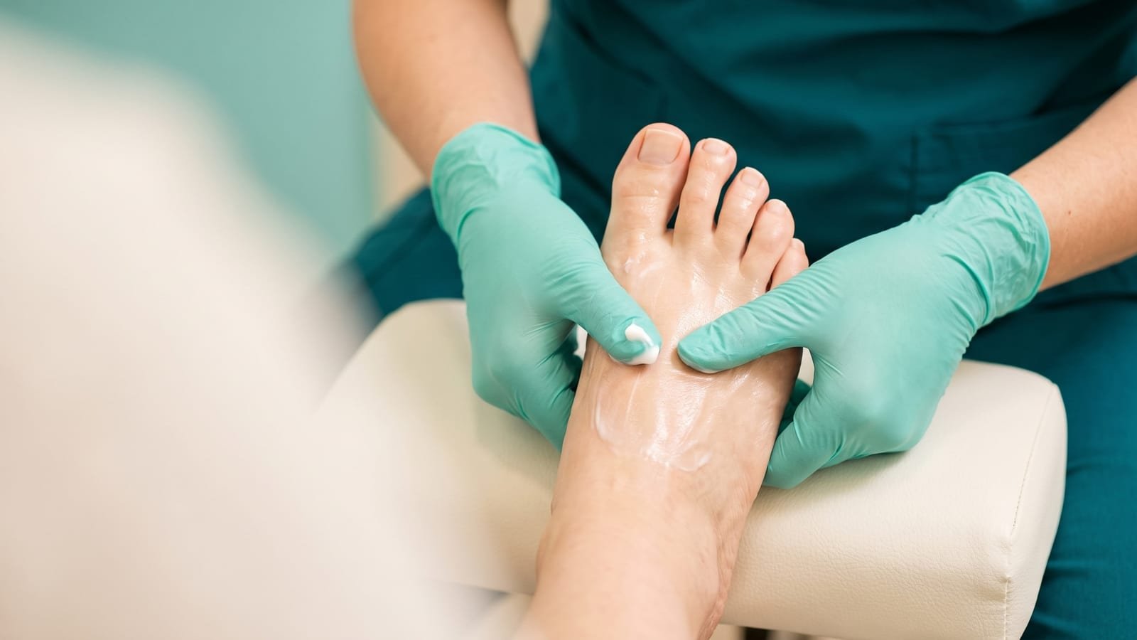 Podóloga massageando creme hidratante no pé ao final da sessão de profilaxia